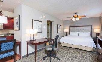 a hotel room with a bed , desk , chair , and television is shown in the image at Homewood Suites by Hilton Bloomington