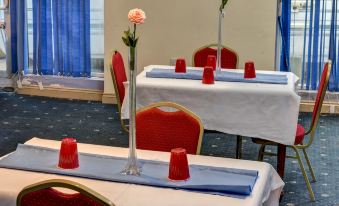 a conference room set up for a meeting , with multiple tables and chairs arranged in rows at Empire Hotel