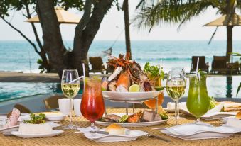 a dining table with a variety of food and drinks , including two wine glasses and a plate of seafood at The Fortress Resort & Spa