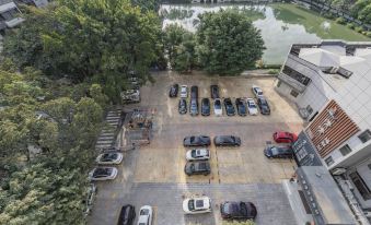 a bird 's eye view of a parking lot with multiple cars parked and trees in the background at Atour Hotel