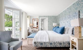 a modern bedroom with a large bed , blue and white bedding , and an open door leading to a balcony at Manoir Hovey