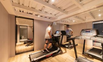 A man is standing in front of a treadmill in his home gym, while another person stands nearby at Weiting Century Hotel