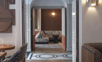 a room with wooden floors , a dining table , chairs , and a couch in the background at Hotel Bachaumont