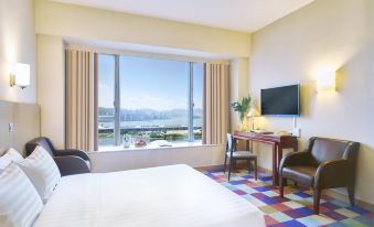 The bedroom features a double bed, desk, and a large window with a city view at Hotel COZI Harbour View