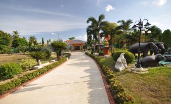 a beautiful entrance to a tropical resort with palm trees , flowers , and a white building at Tokyo Hotel