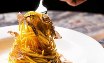 A person is holding a plate of food that includes noodles and sauce in front of them at The Hari Hong Kong