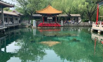 a traditional chinese pavilion is reflected in the water of a tranquil pond , surrounded by lush greenery at Orient Hotel