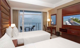 a hotel room with two beds , a desk , and a view of the ocean through a window at Marino Beach Colombo