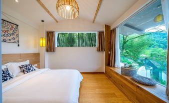 A modern bedroom features large windows and a wooden ceiling, with an open space beside the bed at Little Forest Guesthouse