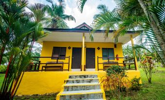 a yellow house surrounded by palm trees , with stairs leading up to the front door at Sea Horizon Resort