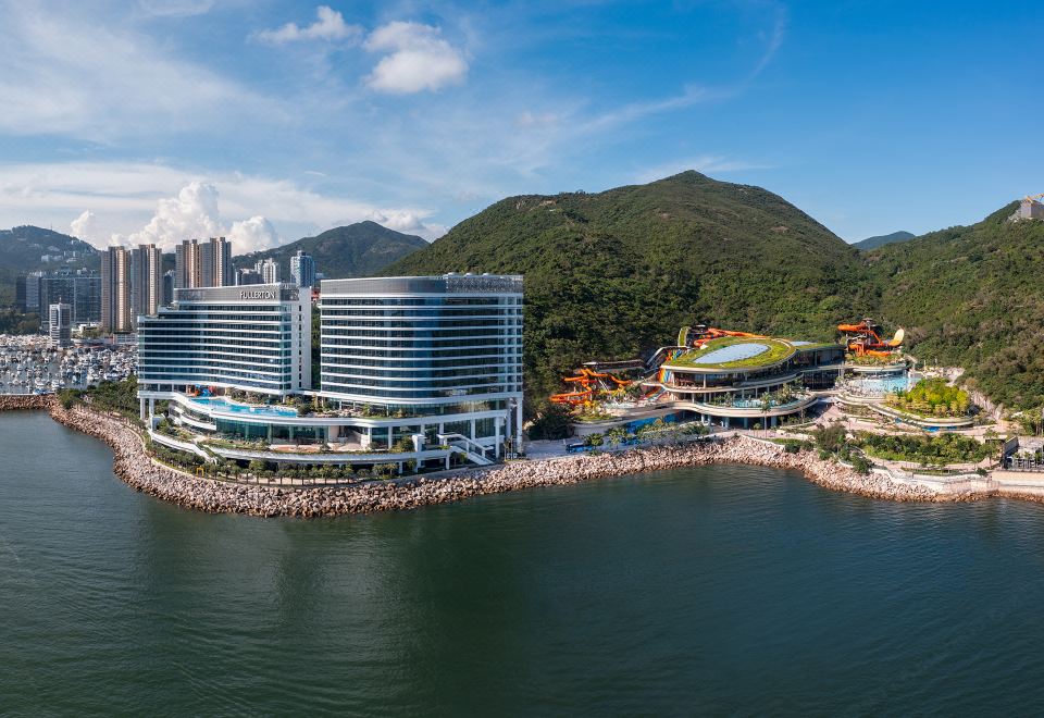 An aerial view showcases a sprawling city bordered by water, including the ocean in the foreground at The Fullerton Ocean Park Hotel Hong Kong