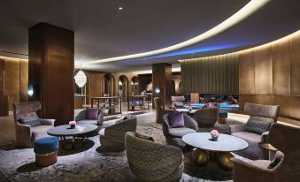 The lobby features tables and chairs arranged in the center, alongside a distinctive area rug at Blossom House Shanghai On The Bund