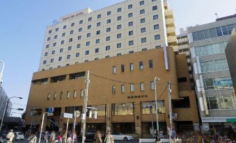 a city street with a tall building on the left side and a hotel on the right side at Kichijoji Tokyu Rei Hotel