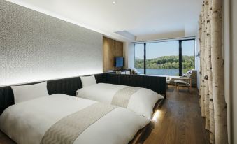 A modern bedroom on an upper floor with large windows and double beds that offer a view of the water at Hoshino Resorts KAI Poroto