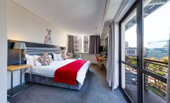 a modern bedroom with a large bed , a desk , and a window overlooking the city at Fountains Hotel