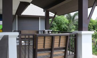 a wooden deck with a table and chairs set up for outdoor dining , surrounded by greenery at Baan Kieng Tawan