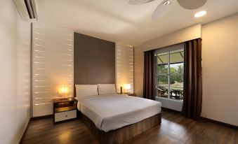 a spacious bedroom with hardwood floors , a large bed , and a window overlooking a balcony at Perhentian Island Resort