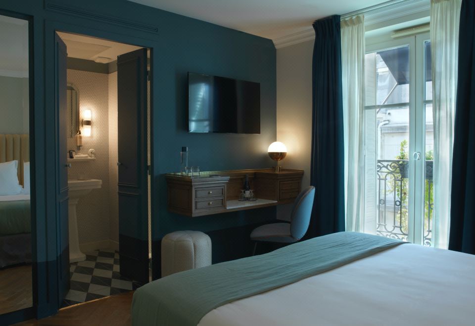 a hotel room with a comfortable bed , a tv , and a desk with a laptop at Hotel Bachaumont