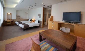 a modern hotel room with two beds , a tv , and a dining table , all decorated in a minimalist style at Kamenoi Hotel Atami Annex