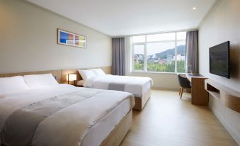 a hotel room with two beds , a desk , and a window , offering a view of a cityscape at Lahan Hotel Jeonju
