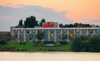 "a large hotel building with a sign that says "" sheraton "" is situated next to a lake" at Washington Dulles Airport Marriott