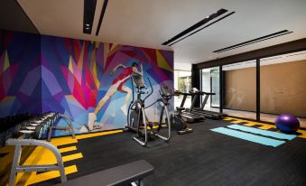 The center features a gym with a large floor-to-ceiling windows and an artistic wall mural at Hampton by Hilton Beijing Guomao CBD