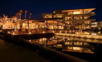 a modern building with a glass facade and large windows , surrounded by trees and water , at night at Malibu Hotel