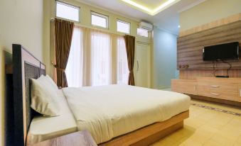 a large bed with white sheets and a wooden headboard is in the center of a room at Super OYO Collection O 2383 Andongkoe 64 Salatiga