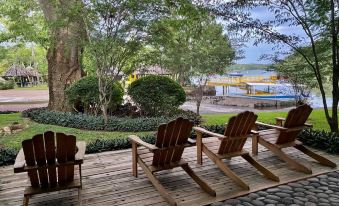 a row of wooden rocking chairs on a wooden deck overlooking a body of water at Puerto Barillas