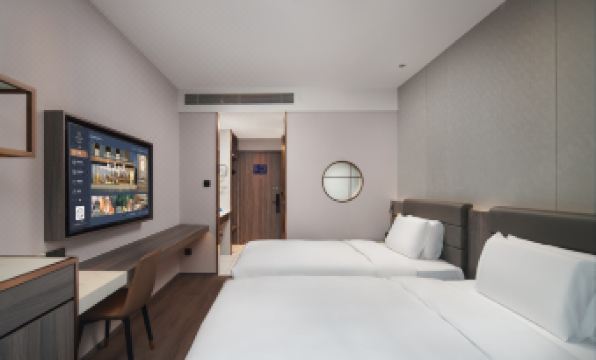 The modern bedroom features double beds and a large screen TV mounted on the wall above each bed at Peony Hotel(Mudanyuan Subway Station)