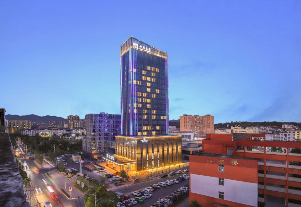 At night, a cityscape is visible with a building in the foreground and a brightly lit hotel on the top floor at Fuzhou Le'an New Century Mingting Hotel