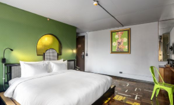 The bedroom features a white bed with a large painting hanging on the wall above it, creating an artistic ambiance at MeStyle Museum Hotel