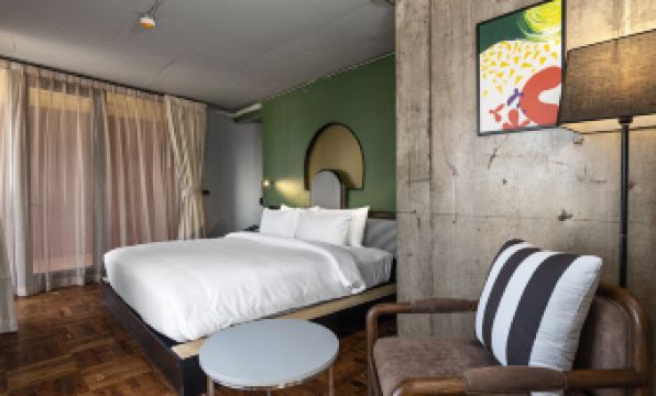 A bedroom with a double bed and a table in the middle, adjacent to it is an area at MeStyle Museum Hotel