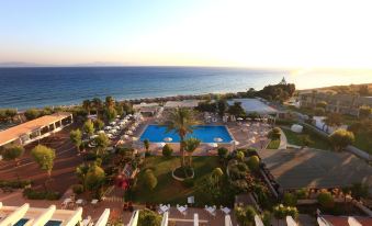 aerial view of a resort near the ocean , with a large pool and palm trees in the background at Labranda Blue Bay Resort
