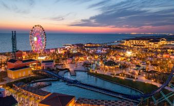 a beautiful amusement park at dusk , with a ferris wheel and a roller coaster visible in the distance at Rixos Water World Aktau