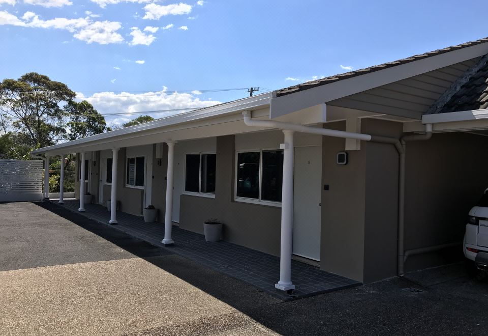 a row of three - story buildings with white roofs , some of which have covered porches and windows at Ulladulla Motel