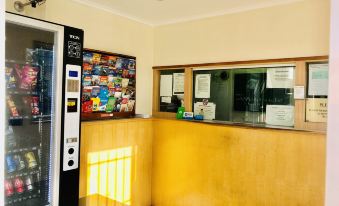 a modern office space with a yellow reception area , vending machines , and other facilities , under the yellow ceiling at Westside Motor Inn