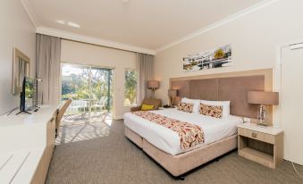 a large bed with a white comforter and pillows is in the middle of a room with a window at Joondalup Resort