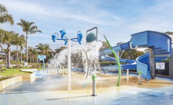 a water park with various water features , such as fountains and sprayers , creating a fun and exciting atmosphere at NRMA Merimbula Beach Holiday Resort