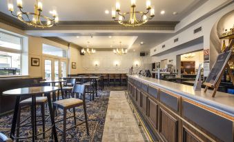 a large , well - lit bar area with several tables and chairs , as well as a reception desk at Nightcap at Pymble Hotel