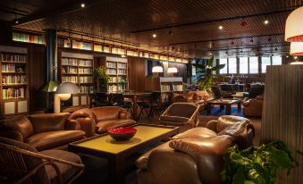 a cozy living room with leather couches , chairs , and a coffee table , surrounded by bookshelves filled with books at The Standard London