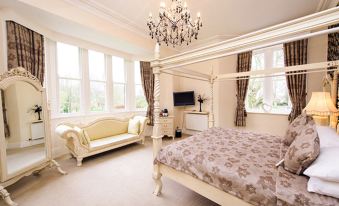 a luxurious bedroom with a large four - poster bed , a couch , and a chandelier hanging from the ceiling at The Old Lodge