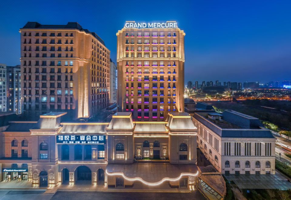 The illuminated building behind it creates a picturesque view of the city at night at Grand Mercure Hangzhou Zijingang