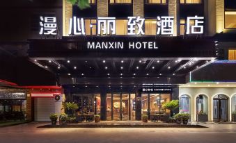 The hotel's front entrance is illuminated at night, displaying a welcoming sign above it at Manxin Hotel