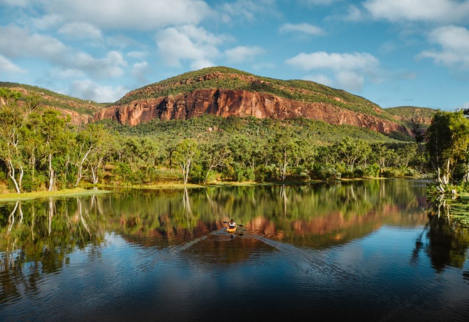 a serene landscape of a lake surrounded by lush greenery and a mountain in the background at Mt Mulligan Lodge