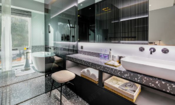 There is a bathroom adjacent to two black objects, featuring double sinks and a large mirror positioned above the bathtub at Insio Hotel (Shenzhen Shekou Maritime World)