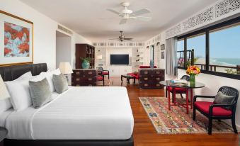 a large , white bed is in a room with wooden floors and red chairs around a desk at Anantara Hua Hin Resort