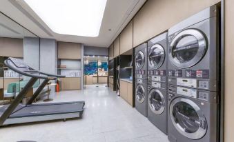 A spacious room with laundry facilities, including washing machines and dryers, located in the adjacent laundry area at Ji Hotel (Shanghai Jing'an Temple Kangding Road)