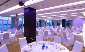 a large banquet hall with white tablecloths , chairs , and wine glasses set up for a formal event at Amfora Hvar Grand Beach Resort