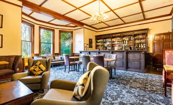 a well - decorated living room with comfortable furniture , including a couch , chairs , and a dining table at Woodland Manor Hotel